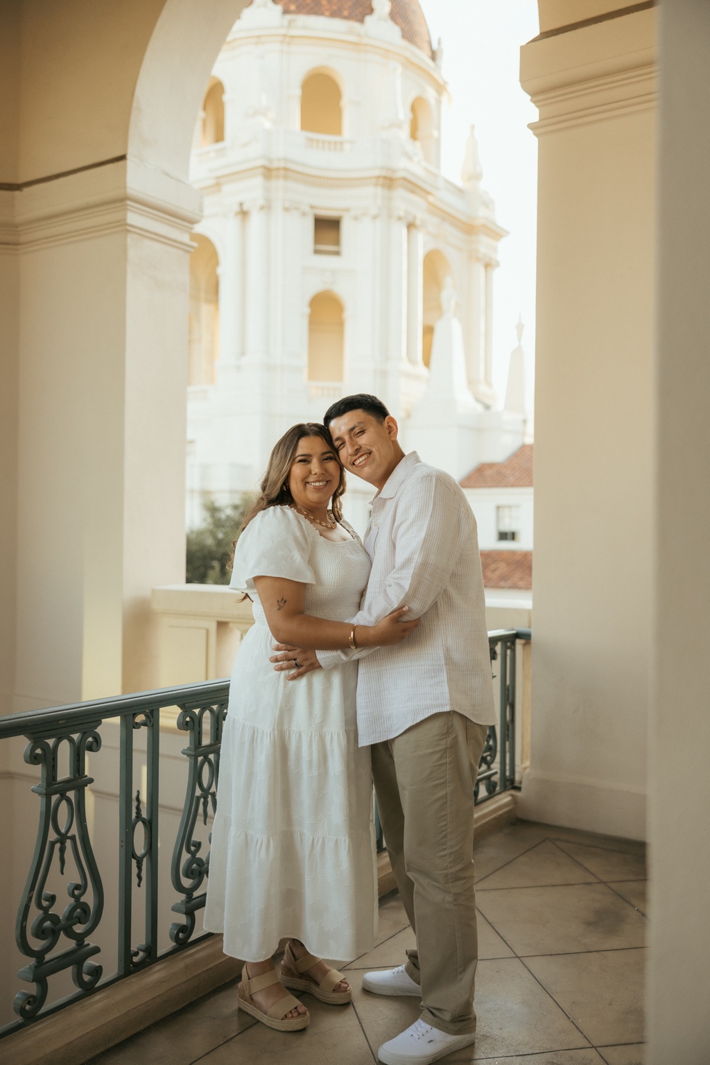 Natalie and Julian smiling and embracing beneath an archway